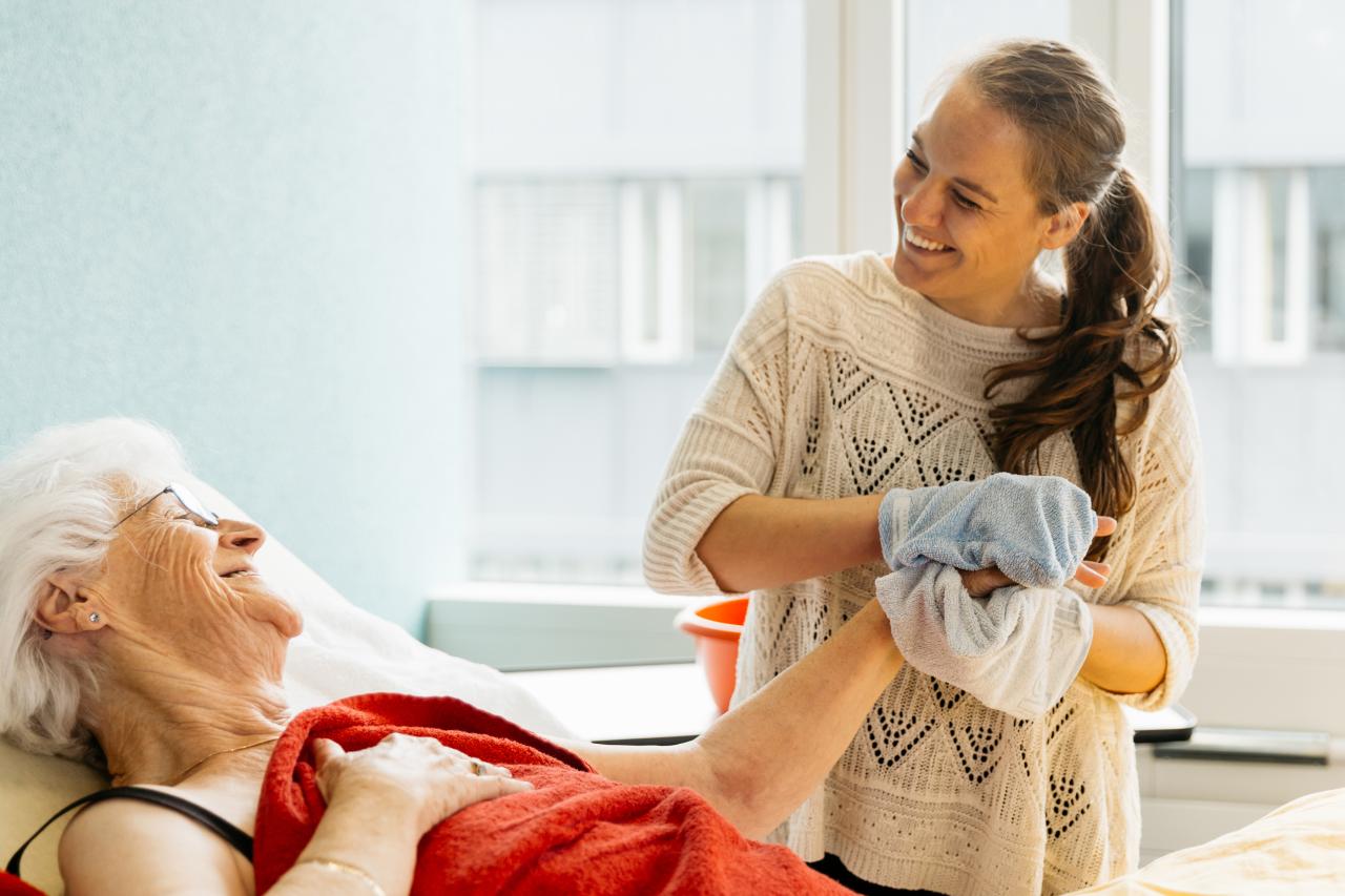 Une auxiliaire de santé traite une personne âgée alitée.
