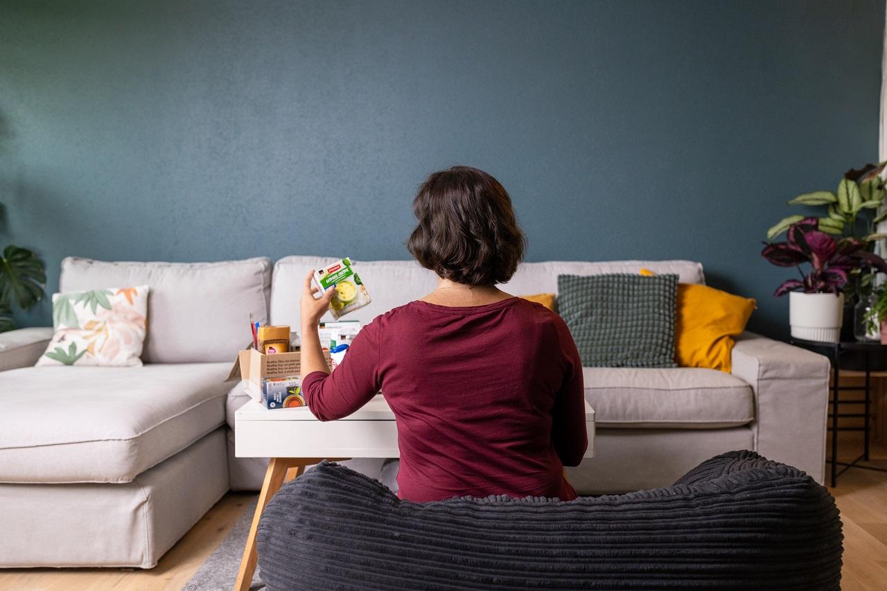 Eine Frau oeffnet ein Paket mit Lebensmitteln