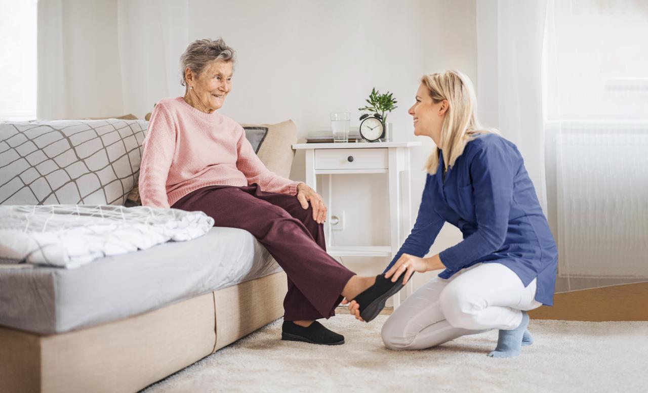 Frau hilft älterer Dame den Schuh anzuziehen
