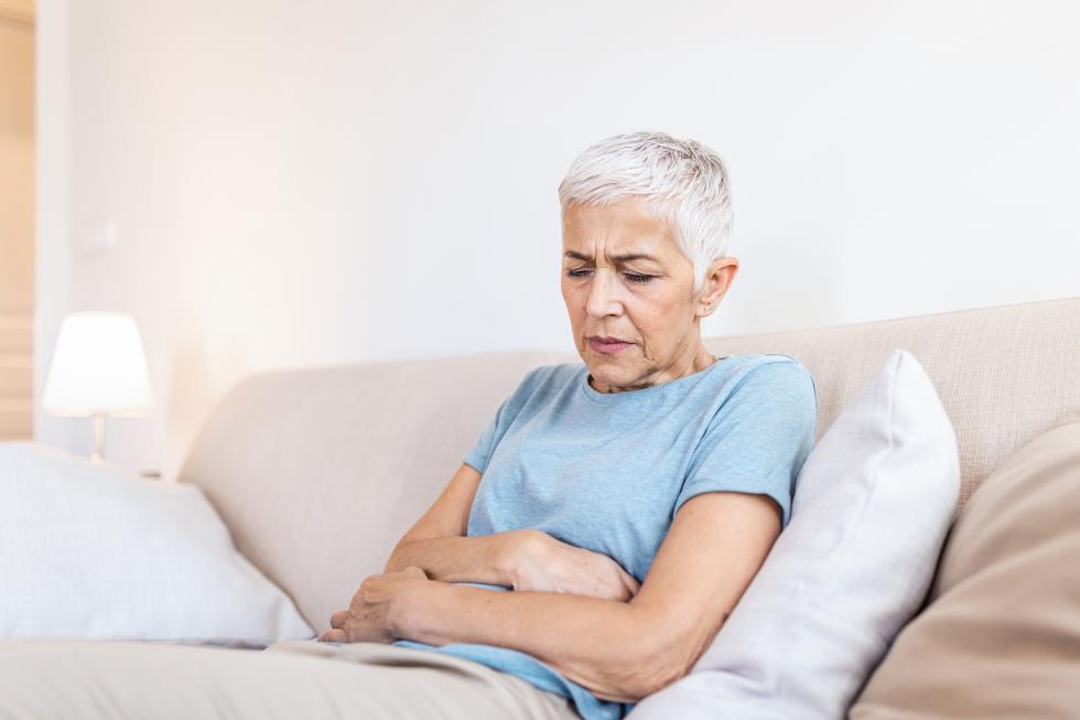 Personne dans une posture qui révèle des douleurs au niveau du ventre.