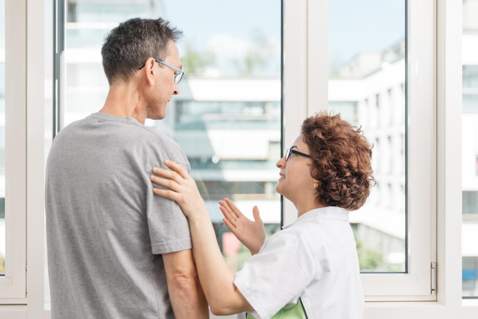 Pflegehelfende spricht einem Angstpatienten Mut zu.