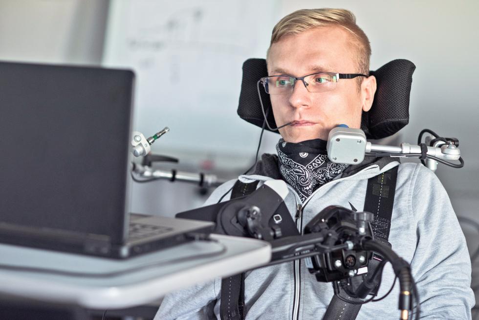 Person steuert Computer mit elektronischen Hilfsmitteln