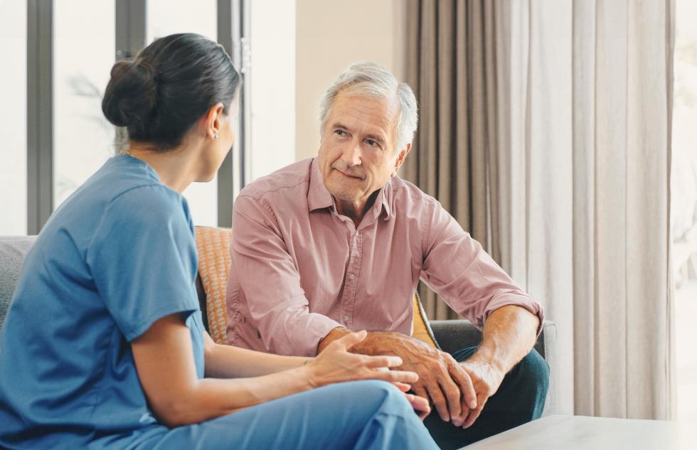 Pflegehelferin und ältere Mann in einer Besprechung