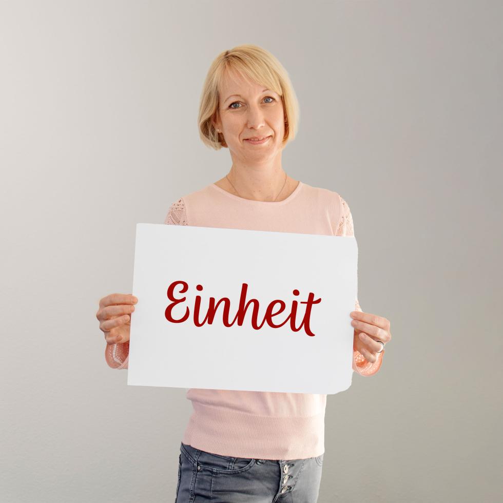 Cornelia Bischoff, Ergotherapeutin beim SRK, hält ein Plakat mit der Aufschrift Einheit in die Kamera.